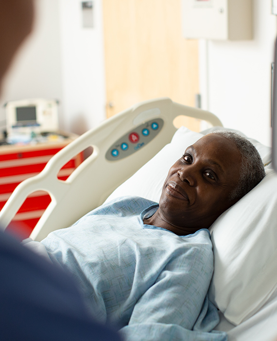 African American woman in a hospital bed speaking to a nurse.